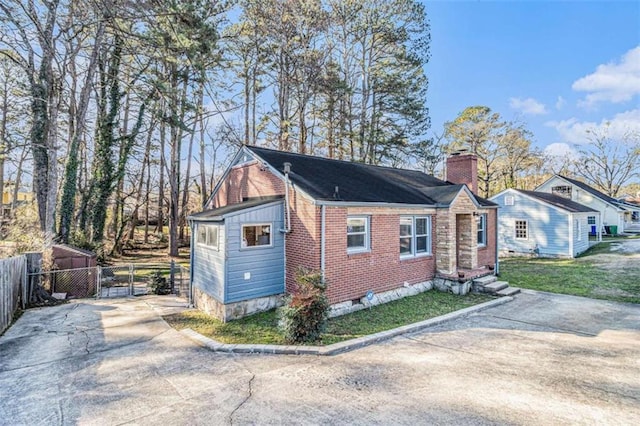 view of front of property with brick siding, fence, crawl space, a front lawn, and a chimney