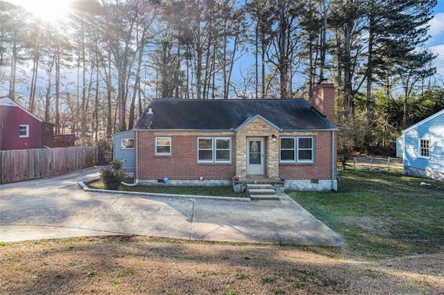 view of front of home with brick siding, fence, concrete driveway, crawl space, and a front yard