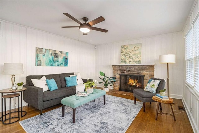 living area featuring ceiling fan, a fireplace, visible vents, and wood finished floors