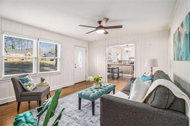 living area with baseboards, a ceiling fan, and wood finished floors