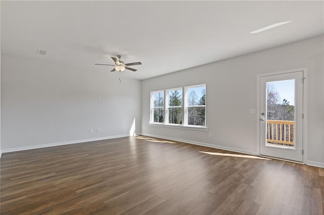 spare room with ceiling fan, visible vents, baseboards, and dark wood-type flooring