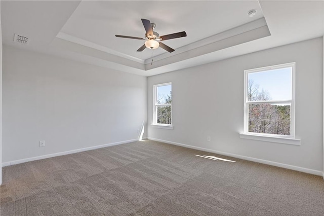 spare room with visible vents, baseboards, ceiling fan, and a tray ceiling