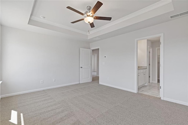 unfurnished bedroom featuring visible vents, baseboards, a tray ceiling, and light colored carpet