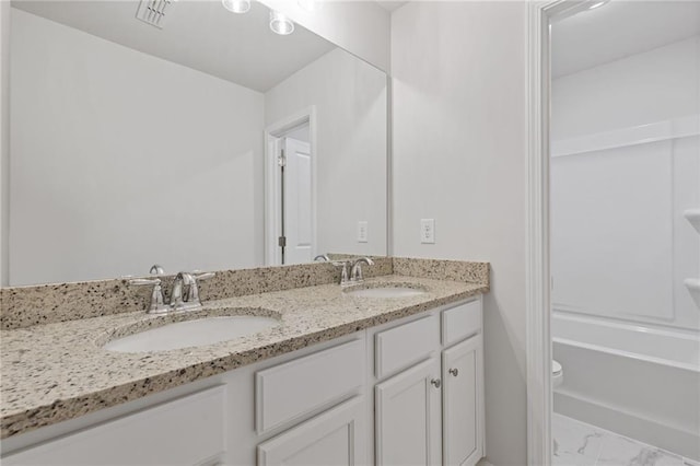 bathroom featuring double vanity, a sink, marble finish floor, and toilet