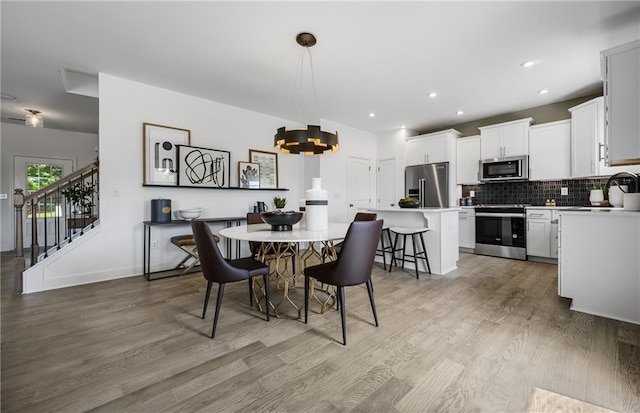 dining room with a notable chandelier, sink, and light hardwood / wood-style floors