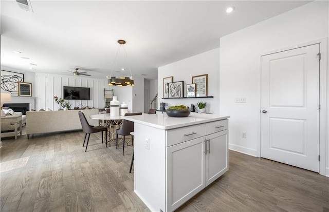 kitchen with white cabinetry, a breakfast bar area, ceiling fan, decorative light fixtures, and a kitchen island