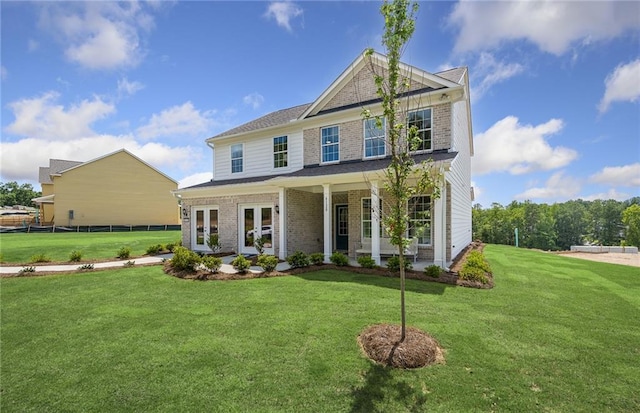 view of front of property with a front yard, covered porch, and french doors