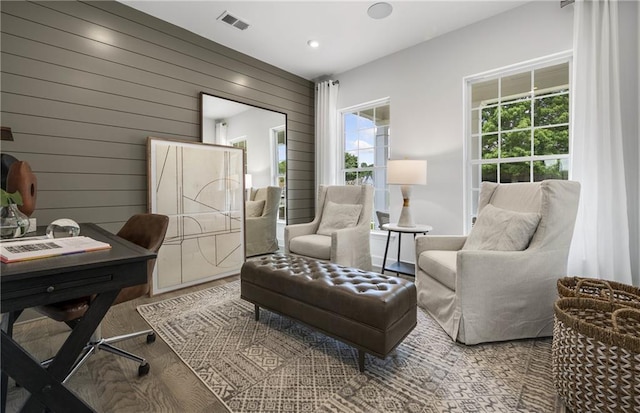 office space featuring a healthy amount of sunlight, wood walls, and hardwood / wood-style flooring