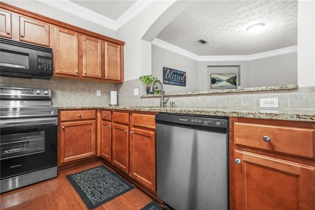 1622 Honeysuckle Path, Conyers, GA 30012 - kitchen with stainless steel appliances, a sink, wood finished floors, brown cabinetry, and ornamental molding