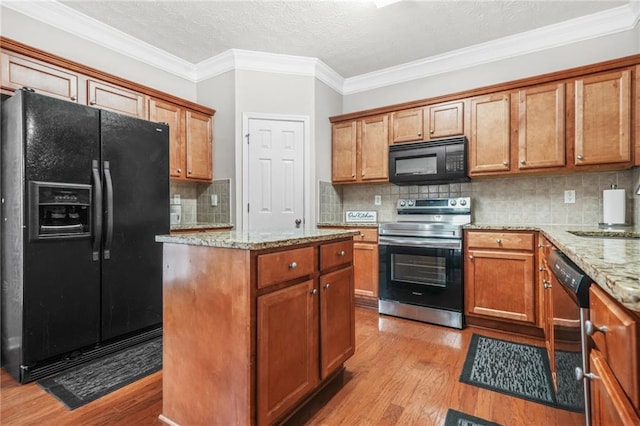 1622 Honeysuckle Path, Conyers, GA 30012 - kitchen with black appliances, light wood finished floors, a center island, brown cabinets, and light stone counters