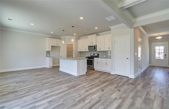 kitchen with sink, a center island with sink, appliances with stainless steel finishes, white cabinets, and backsplash