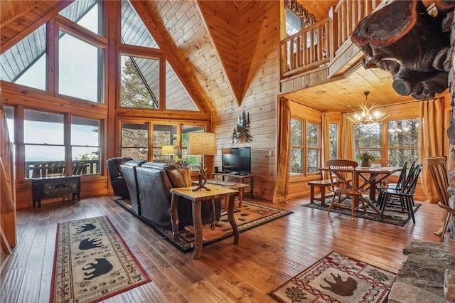 living room with wooden walls, high vaulted ceiling, dark hardwood / wood-style flooring, wooden ceiling, and an inviting chandelier