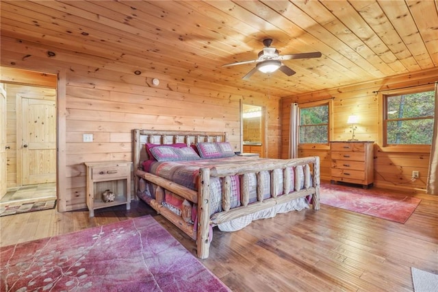 bedroom with ceiling fan, ensuite bathroom, light wood-type flooring, wooden walls, and wooden ceiling