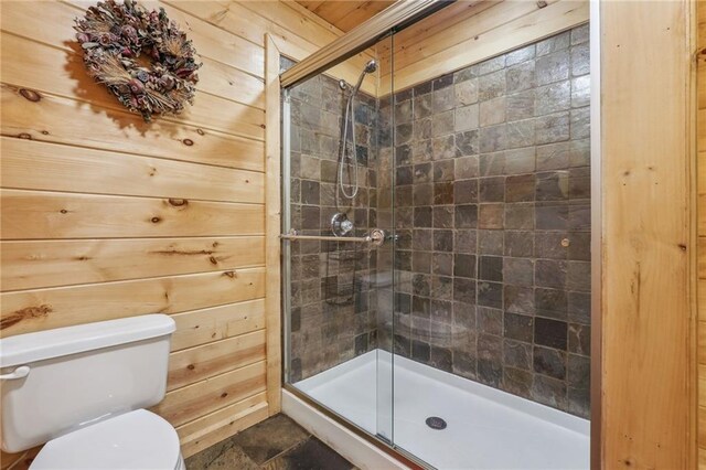 bathroom featuring wooden walls, an enclosed shower, toilet, and tile flooring