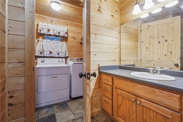 bathroom with washing machine and clothes dryer, wood walls, oversized vanity, and tile flooring