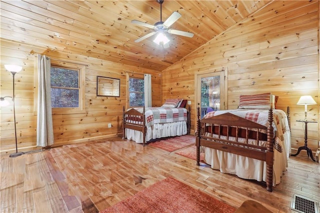 bedroom featuring ceiling fan, vaulted ceiling, wooden walls, wooden ceiling, and light wood-type flooring