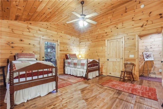 bedroom with wood ceiling, wood walls, light hardwood / wood-style flooring, and ceiling fan