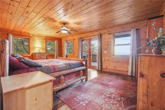 bedroom with wood walls, dark hardwood / wood-style flooring, and access to outside