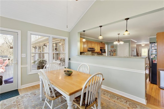 dining space with lofted ceiling, ornamental molding, a healthy amount of sunlight, and light wood-type flooring