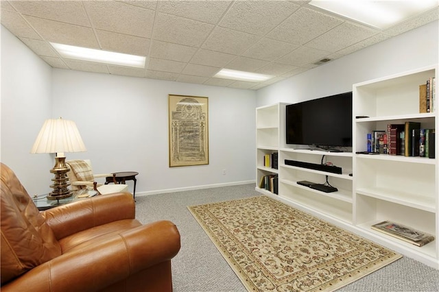 carpeted living room featuring a drop ceiling