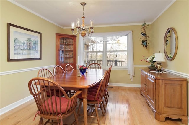 dining area featuring crown molding, an inviting chandelier, and light hardwood / wood-style flooring