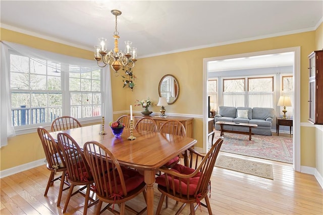 dining space with ornamental molding, a notable chandelier, and light wood-type flooring