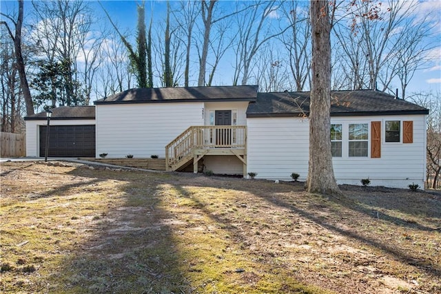 rear view of property featuring a garage and a lawn