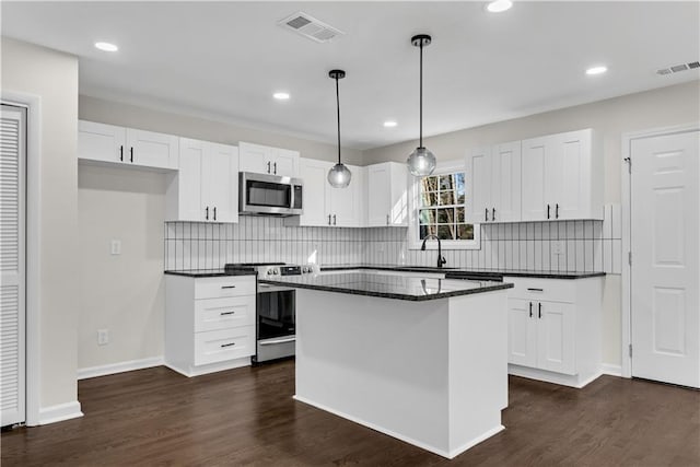 kitchen with stainless steel appliances, sink, pendant lighting, a center island, and white cabinetry