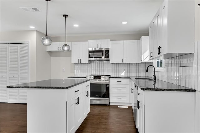 kitchen featuring a center island, sink, appliances with stainless steel finishes, decorative light fixtures, and white cabinetry