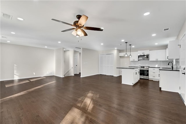 unfurnished living room with dark hardwood / wood-style flooring, ceiling fan, and sink