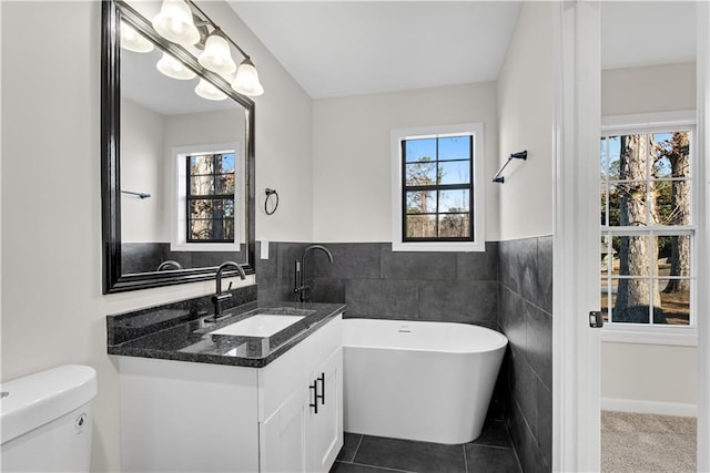 bathroom featuring a wealth of natural light, tile patterned flooring, tile walls, and a washtub