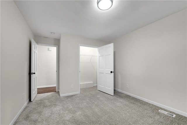 unfurnished bedroom with light colored carpet and a closet