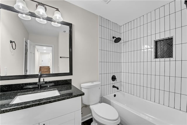 full bathroom featuring vanity, tiled shower / bath combo, and toilet