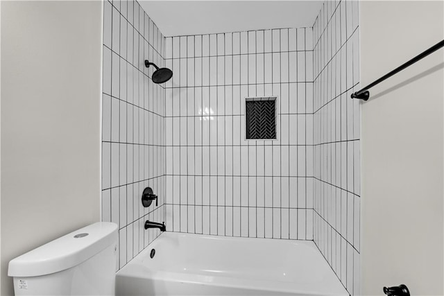 bathroom with tiled shower / bath combo and toilet