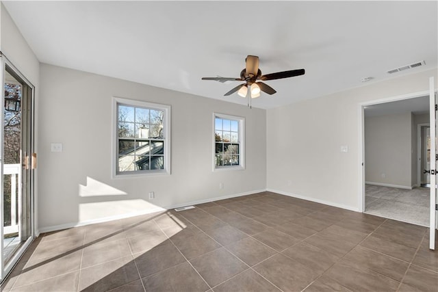 unfurnished room with ceiling fan and dark tile patterned flooring