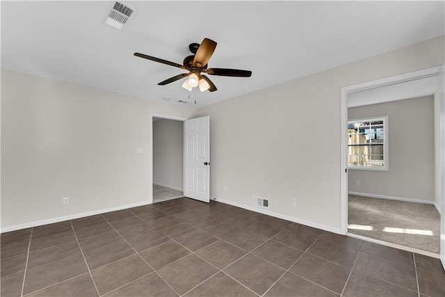 empty room with dark tile patterned floors and ceiling fan