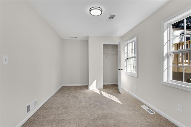 unfurnished bedroom with light colored carpet and a closet