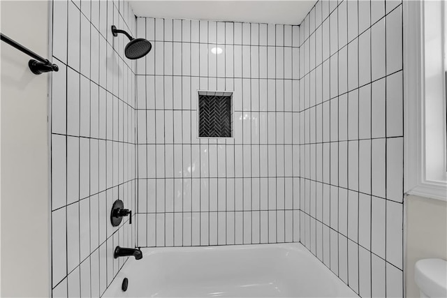 bathroom featuring toilet and tiled shower / bath