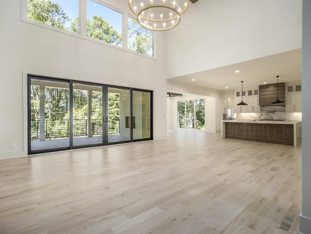 unfurnished living room with light wood-type flooring, a high ceiling, and a wealth of natural light