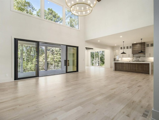 unfurnished living room featuring a high ceiling and light hardwood / wood-style floors