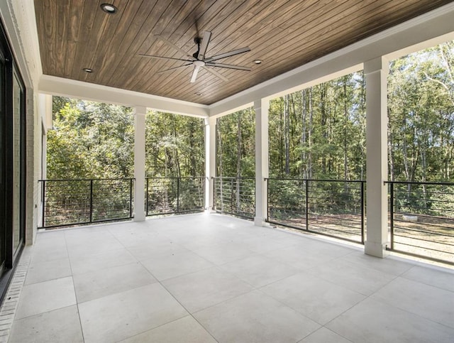 unfurnished sunroom with ceiling fan, a wealth of natural light, and wooden ceiling