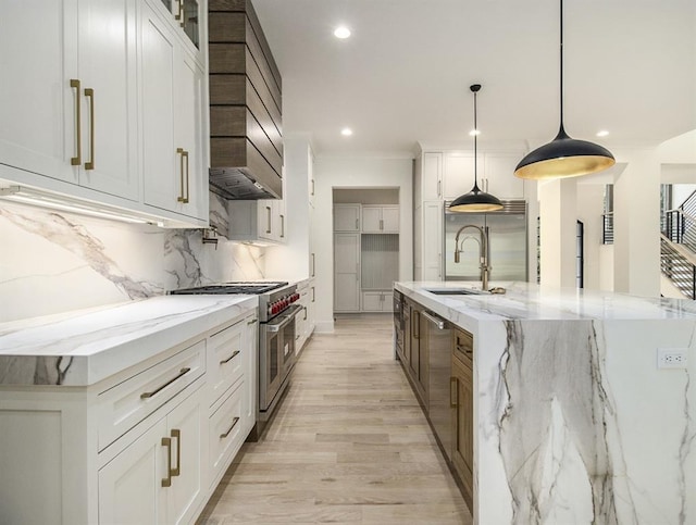 kitchen with white cabinets, light stone counters, a spacious island, and high quality appliances