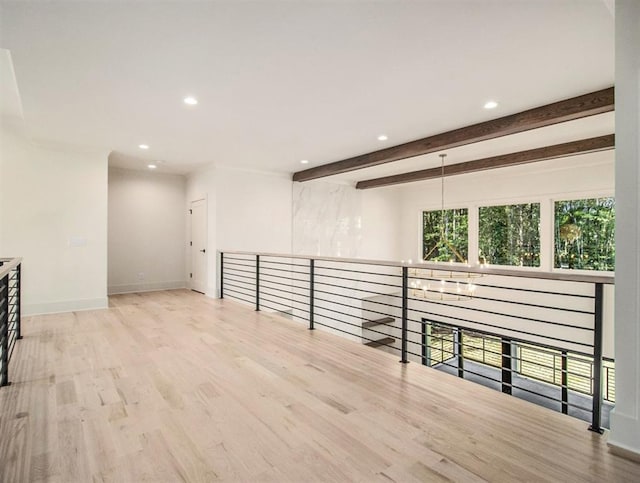 spare room with beamed ceiling and light hardwood / wood-style flooring