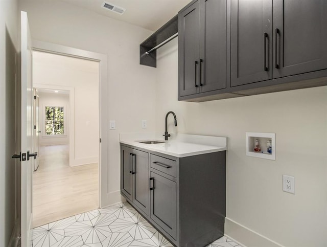 laundry area featuring cabinets, washer hookup, light tile patterned floors, and sink