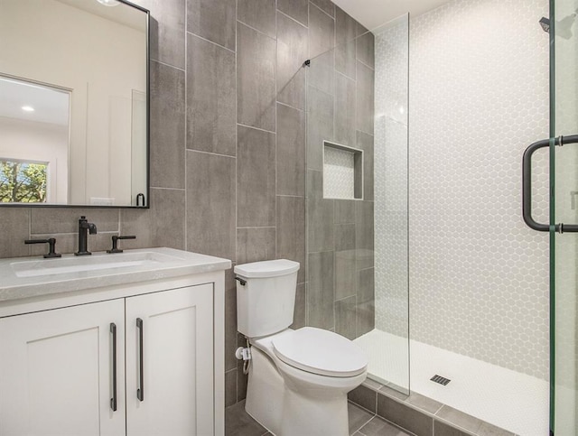 bathroom featuring vanity, tile patterned flooring, a shower with shower door, tile walls, and toilet