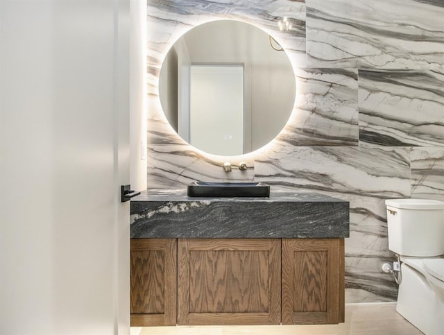 bathroom featuring vanity, tile walls, and toilet