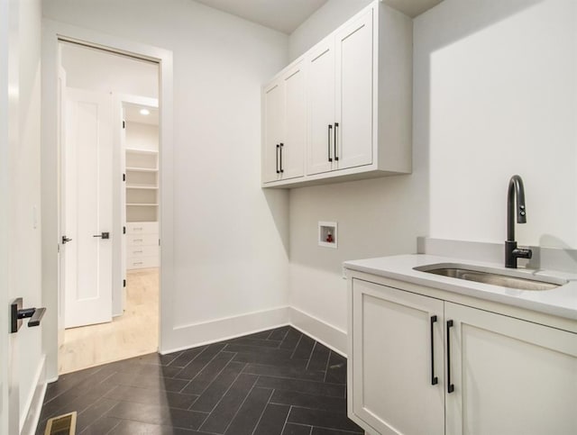 laundry area featuring hookup for a washing machine, sink, dark wood-type flooring, and cabinets