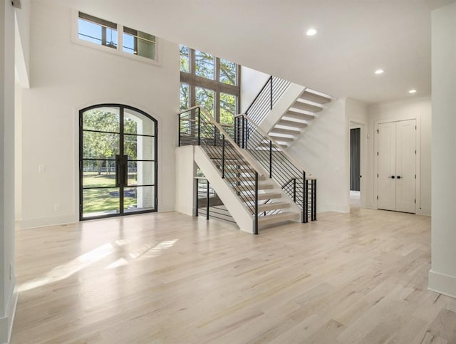 entrance foyer with a towering ceiling and light hardwood / wood-style floors