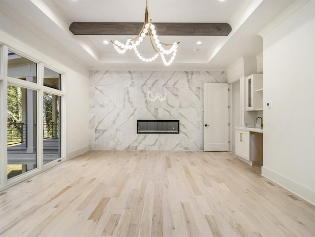 unfurnished living room featuring light hardwood / wood-style flooring, a notable chandelier, and a raised ceiling