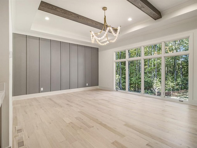 unfurnished room featuring a healthy amount of sunlight, beamed ceiling, and a notable chandelier